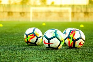 A group of footballs on a grassy field, symbolizing the game of football and highlighting common injuries, including leg, calf, hip, and serious football injuries, and their management.