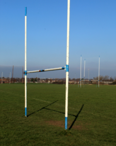 A football goal post on a grassy field, symbolizing the game of football and the risks of common knee and ankle injuries in football and Gaelic football.