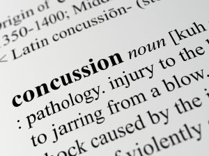 A close-up image of the word "concussion" in a dictionary, highlighting the significance of head injuries in sports and their impact on athletes.