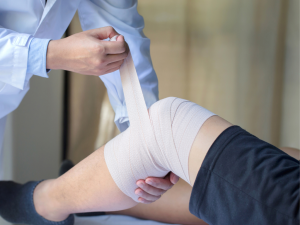 A medical professional applying an elastic support bandage on a knee, demonstrating its use for knee injuries, sprains, and as a tubular support bandage