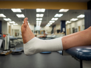 A close-up of an ankle wrapped with sports injury support tape using athletic taping techniques, providing stability and protection for athletic injuries during recovery or activity
