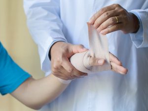 A healthcare professional wrapping a patient's hand with a self-adhesive elastic bandage, providing secure support and flexibility for injury care.