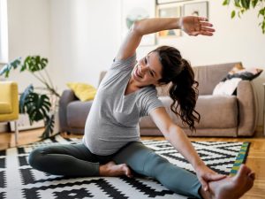 Pregnant woman practicing Pilates at home on a comfortable rug, showcasing the benefits and safety of Pilates during pregnancy