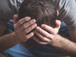 A distressed individual holding their head, symbolizing psychological injury and the mental impact of stress or trauma, including issues caused by employers or sports-related injuries.