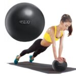 Black Pilates Ball 22cm-A woman demonstrates a push-up exercise with the ball for Pilates and fitness routines.