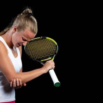 Female tennis player holding her elbow in pain, showing symptoms of tennis elbow