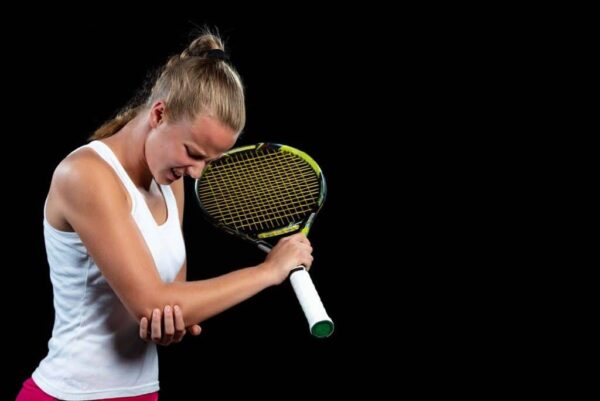 Female tennis player holding her elbow in pain, showing symptoms of tennis elbow