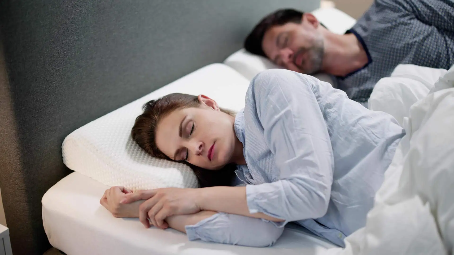 Young couple sleeping on orthopedic pillows to avoid neck and back pain in the mornitngs.