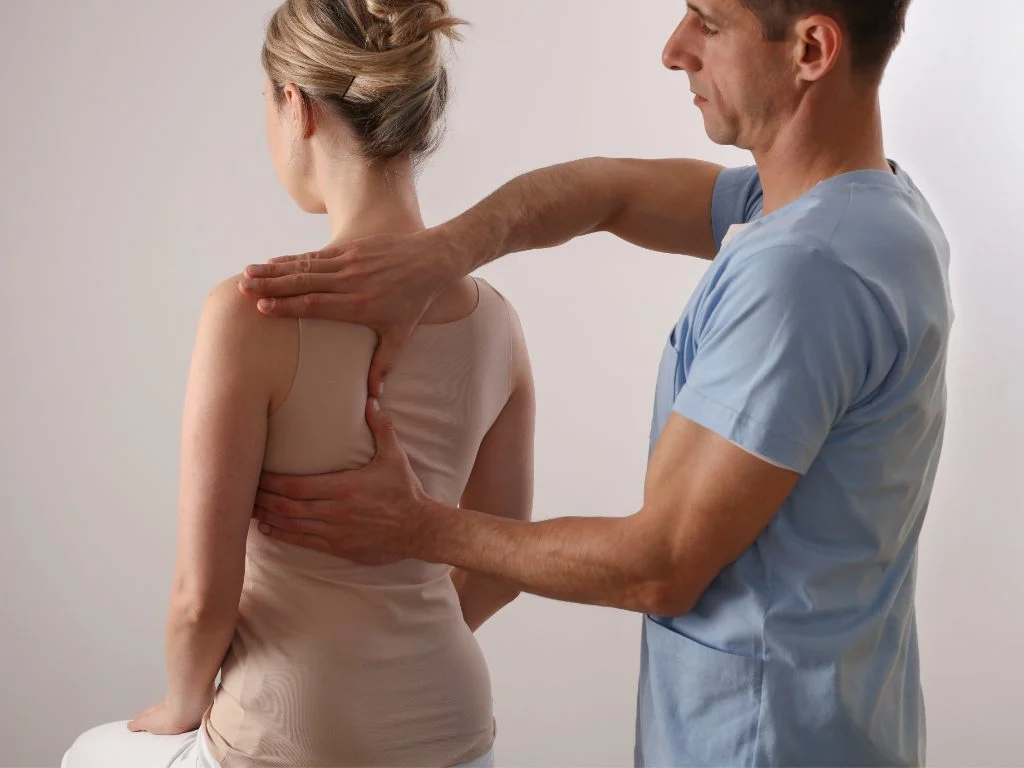 Physio specialist examining the condition of a patient. He is checking her back strength.