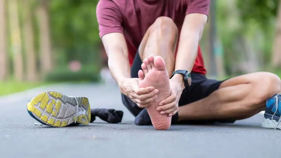 Young man holding his foot in pain.