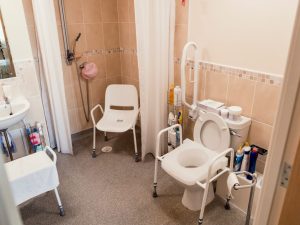 Bathroom aids for the elderly and seniors, featuring grab bars, non-slip mats, and a raised toilet seat, designed to enhance safety and accessibility in the bathroom