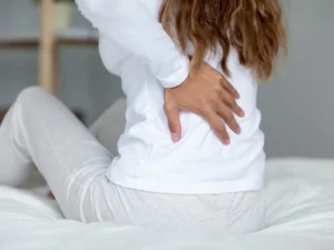 Woman waking up on her bed with strong back pain.