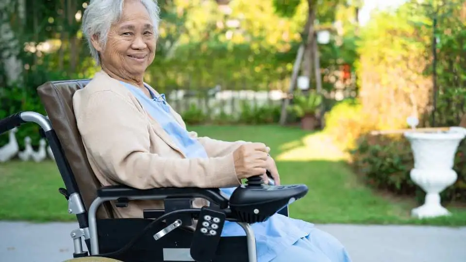 Elderly woman using an electric wheelchair in the care home's garden.