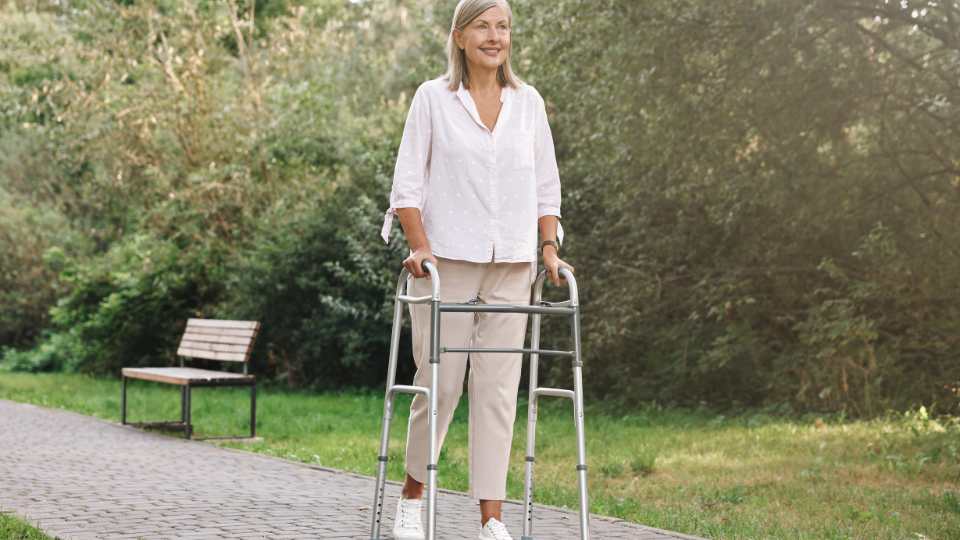 Elderly woman using a zimmer frame in the park. She walks confidently as she inspected the zimmer frame well before use.