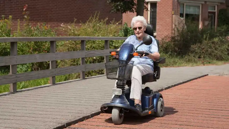 A lady with a mobility scooter enjoys the nice weather in her local park.