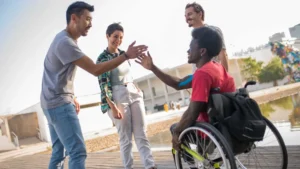 A wheelchair user celebrating with his friends and enjoying the nice weather outside. He chose the right wheelchair for outdoors with large wheels to be able to move independently.