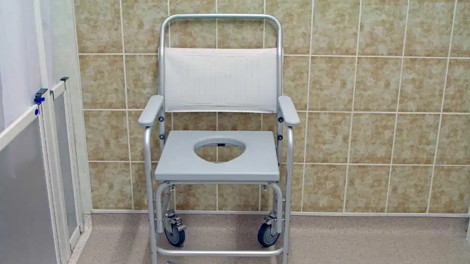 Image illustrating a commode chair inside a bathroom.