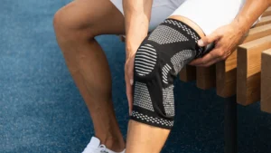 Male wearing an elastic knee support on his left leg correctly to support his knee.