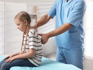 Physical therapist assisting a young patient on a padded treatment table during a rehabilitation session to ensure comfort and effective care