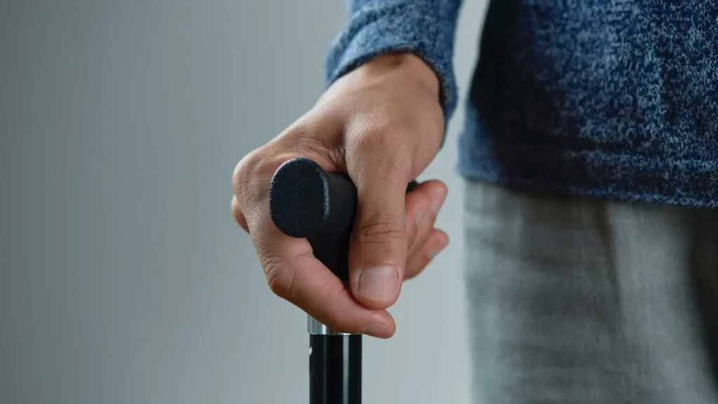 Elderly man who has arthritis in his hands is using a walking cane with ergonomic soft handle.