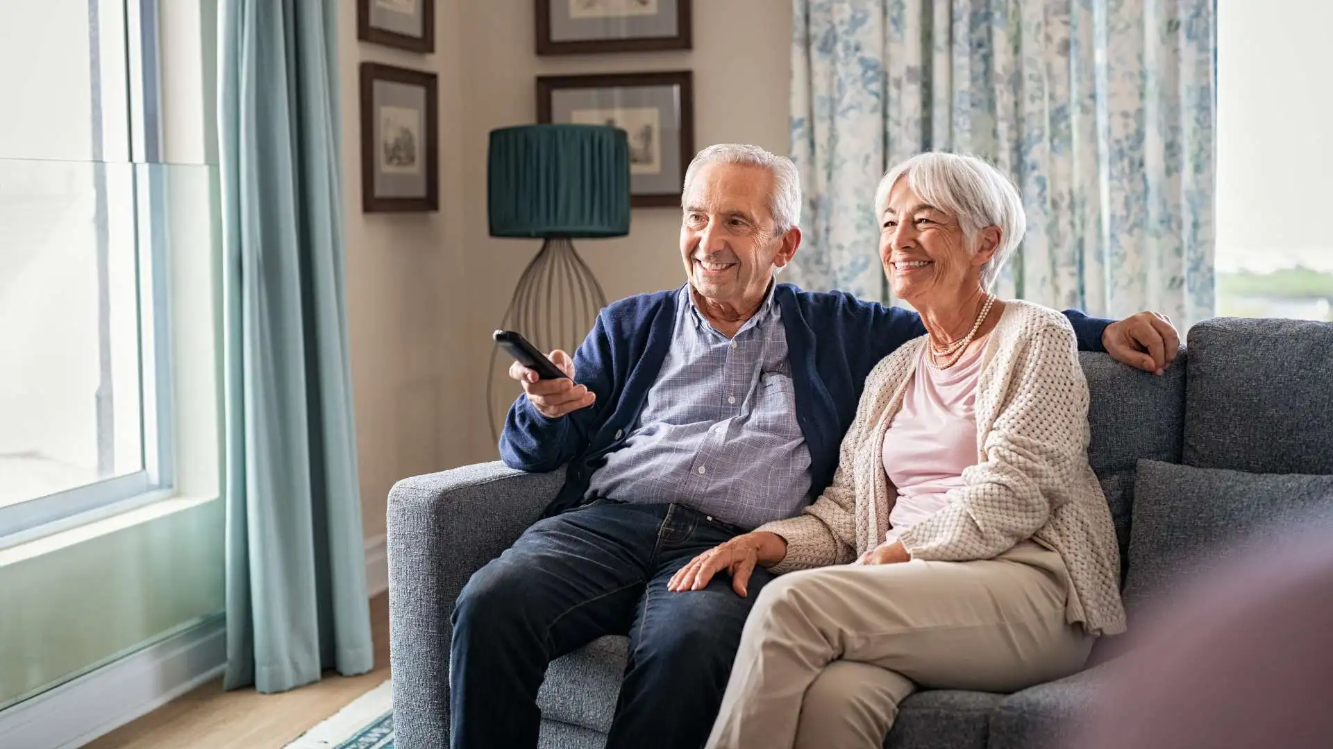 elderly couple sitting on the sofa and watching tv.