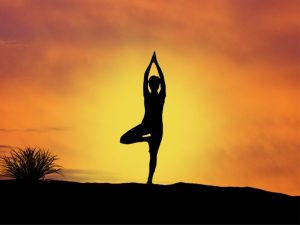 Silhouette of a person practicing yoga at sunrise, symbolizing the connection between mind, body, and spirit while experiencing the benefits of yoga