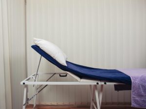 A portable massage table set up in a therapy room, showcasing its adjustable features and compact design for mobile massage services.