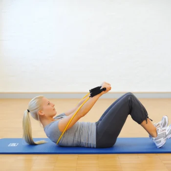 Woman lying on a yoga mat using the SISSEL Fit-Tube for upper body resistance training and stretching exercises.