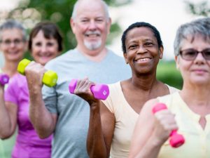 Group of seniors performing functional fitness exercises with colorful dumbbells, promoting strength and improved movement for everyday activities
