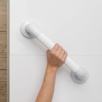 Hand gripping a white textured grab rail securely mounted on a tiled wall