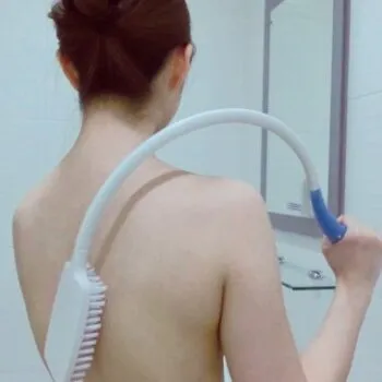 An elderly-friendly curved bath brush with a long handle, shown in use on a person's back for easy showering and bathing.