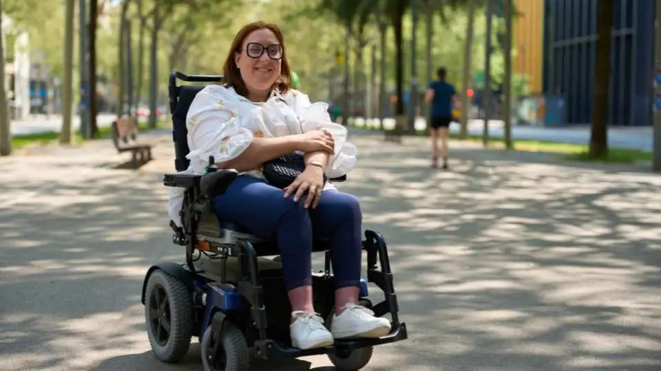 A woman enjoying the weather in the park sitting on her electri powerchair.