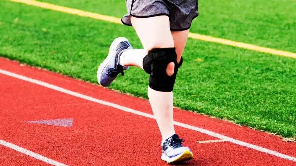 An athlete running whilst wearing knee braces on both legs to help keep the knee stable.