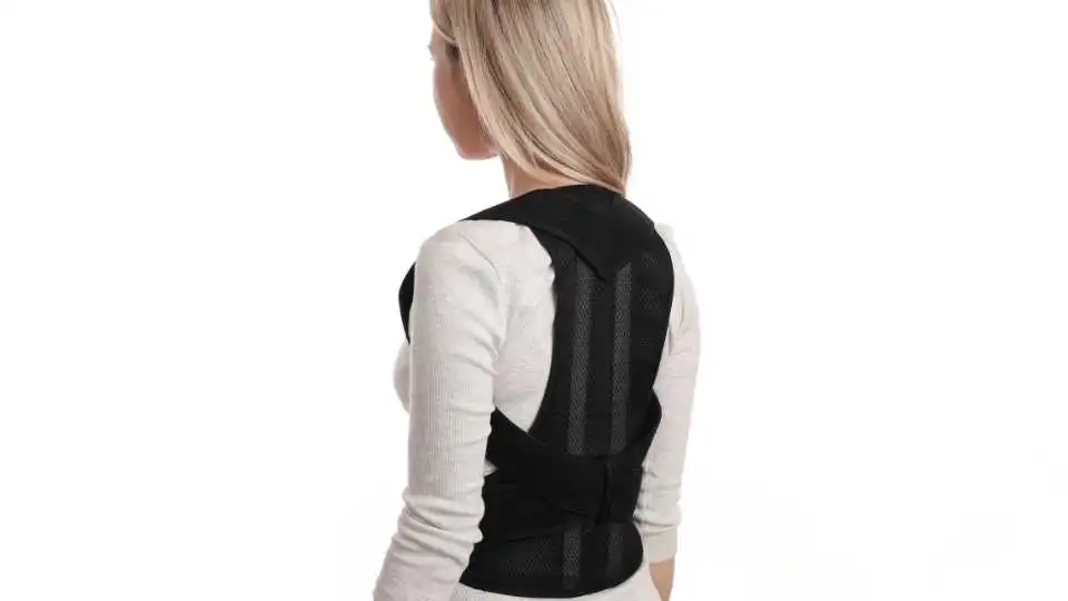 A young woman wearing posture corrector at home.