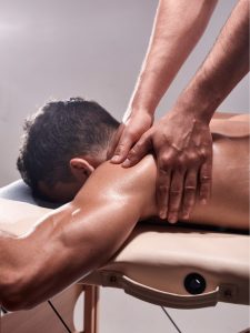 A physiotherapist providing a back massage to a patient on a massage table, highlighting its suitability for home use and professional physiotherapy treatments.