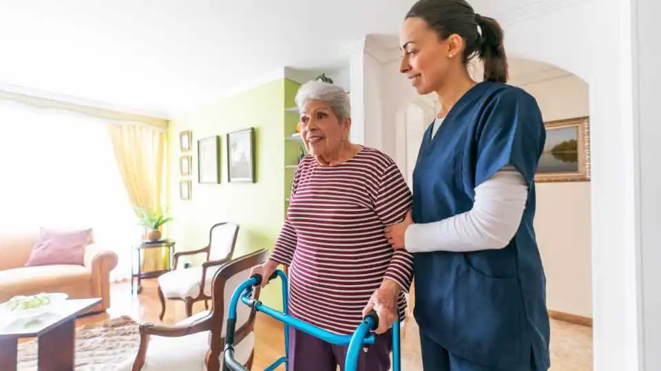 Young caregiver supporting elderly lady learn how to use a rollator walker the right way.