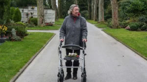 Elderly person using an outdoor rollator walker during an afternoon walk in the park.