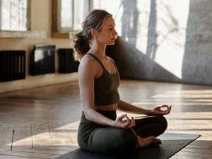 A woman practicing yoga in a serene indoor setting, symbolizing the art of transformation through yoga for body, weight loss, and wellness improvement.