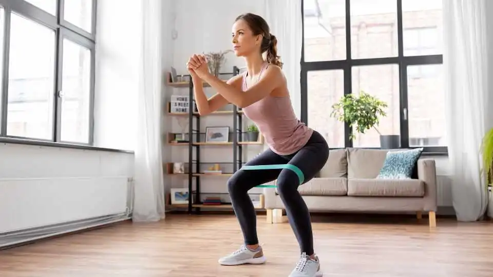 Young woman using resistance bands for squads. She demonstrates how tension increases as you stretch the band further.