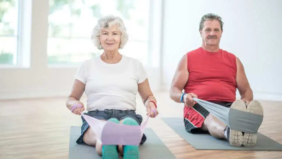 Elderly couple training with resistance bands at home.