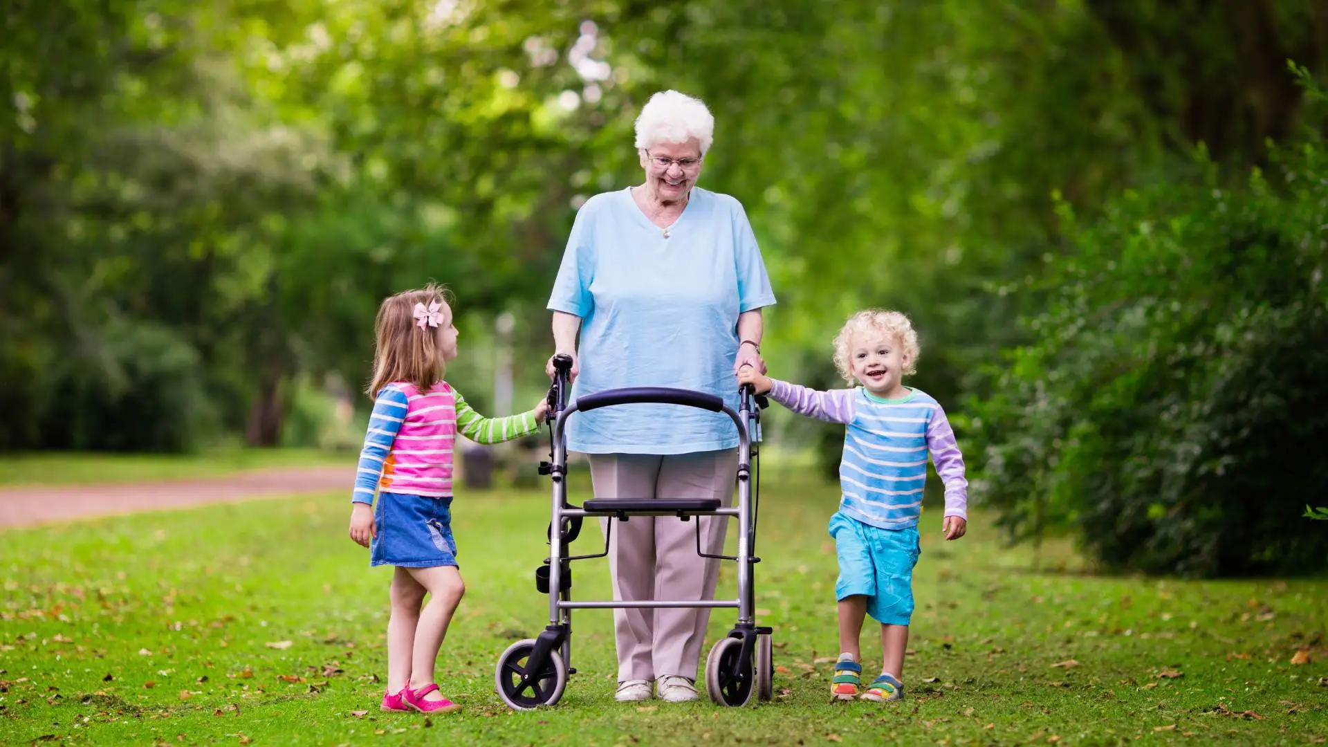 Elderly woman using a rollator and walking in the park with her grandchildren.