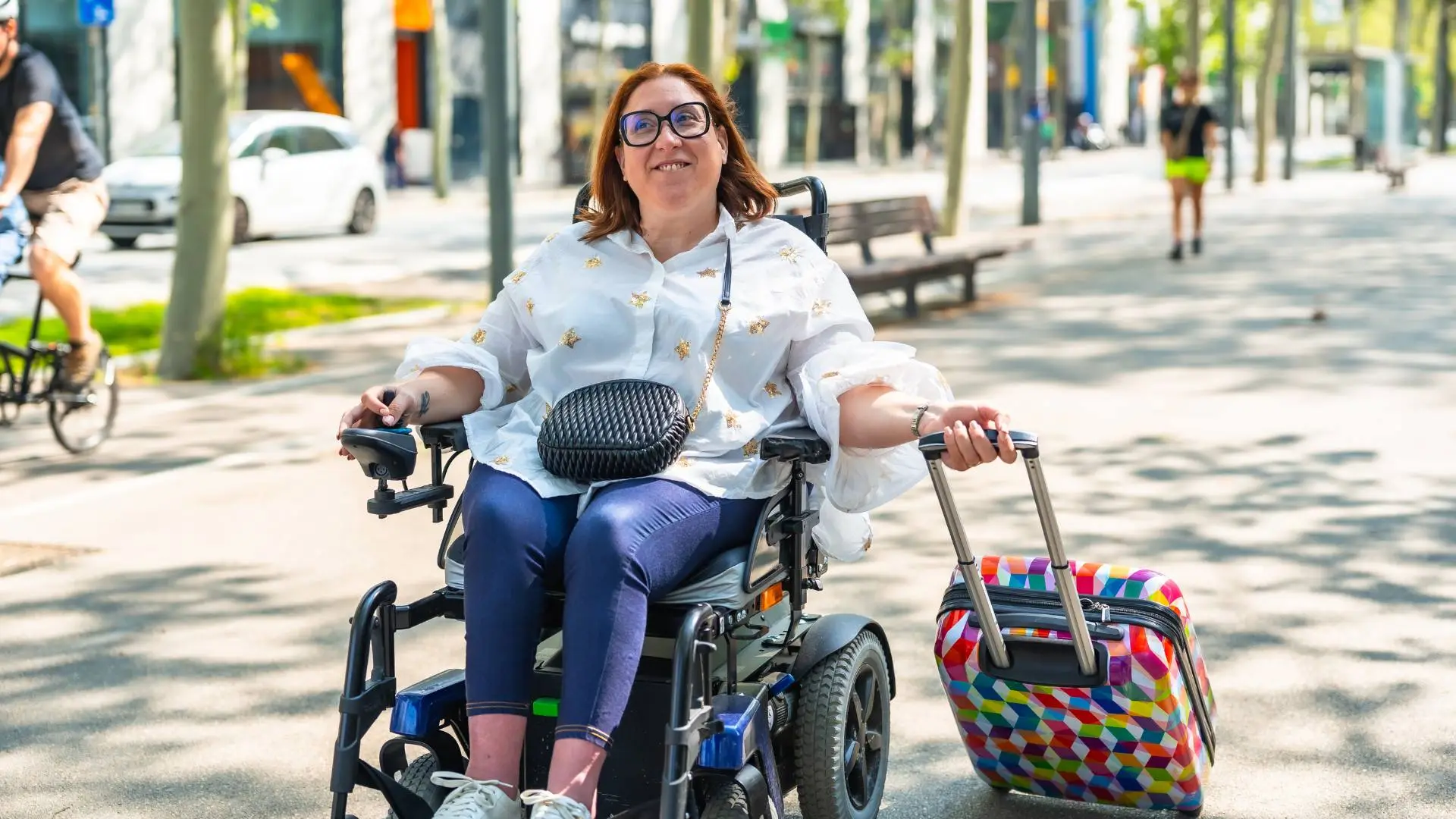 Woman in the park using a power wheelchair while dragging her suitcase