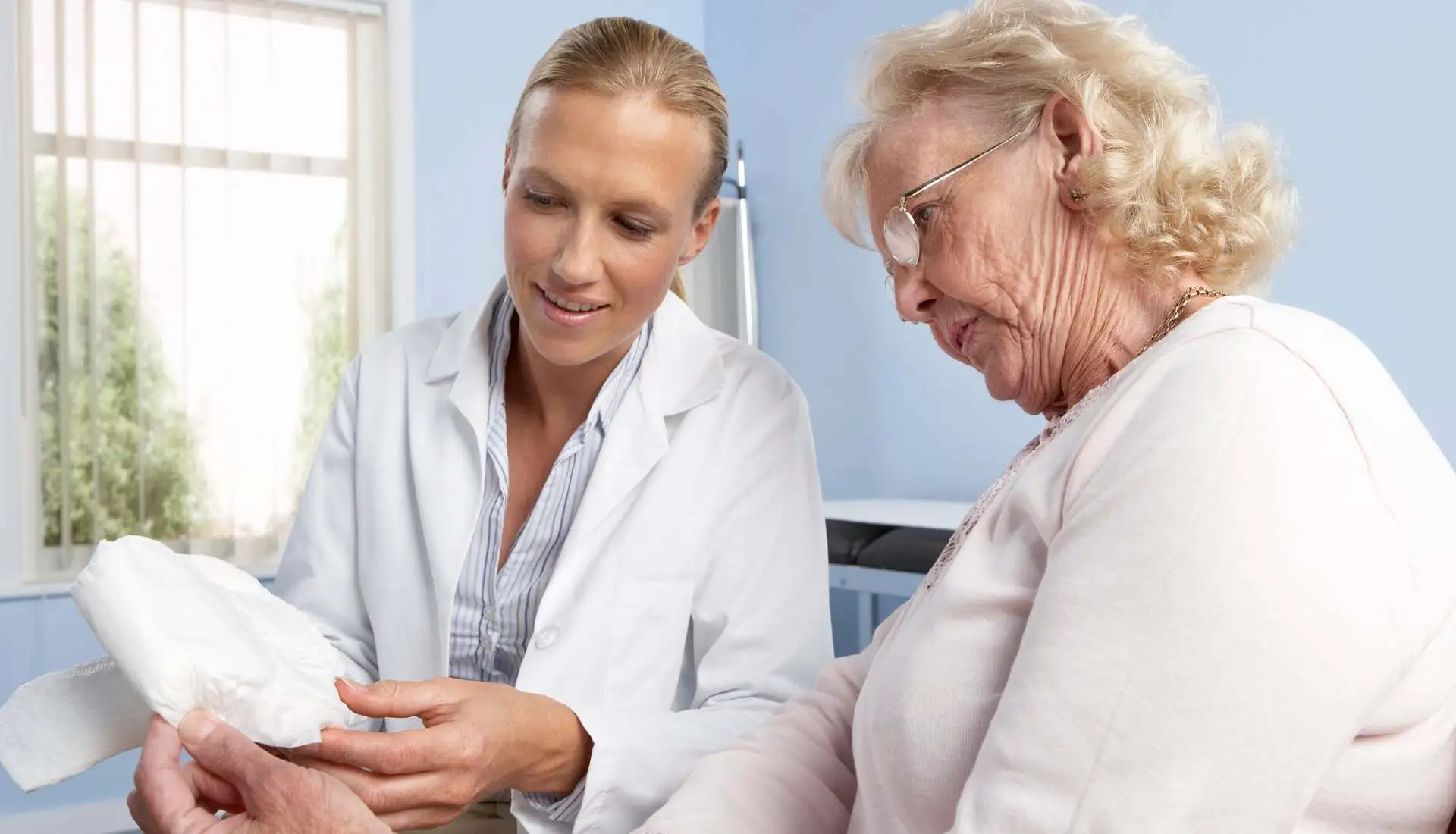 A doctor explains to a patient how to dispose off incontinence pads at home.