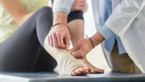 Physio specialist applying bandages to an injured ankle while explaining how comfortable the knee walker is for ankle injuries.
