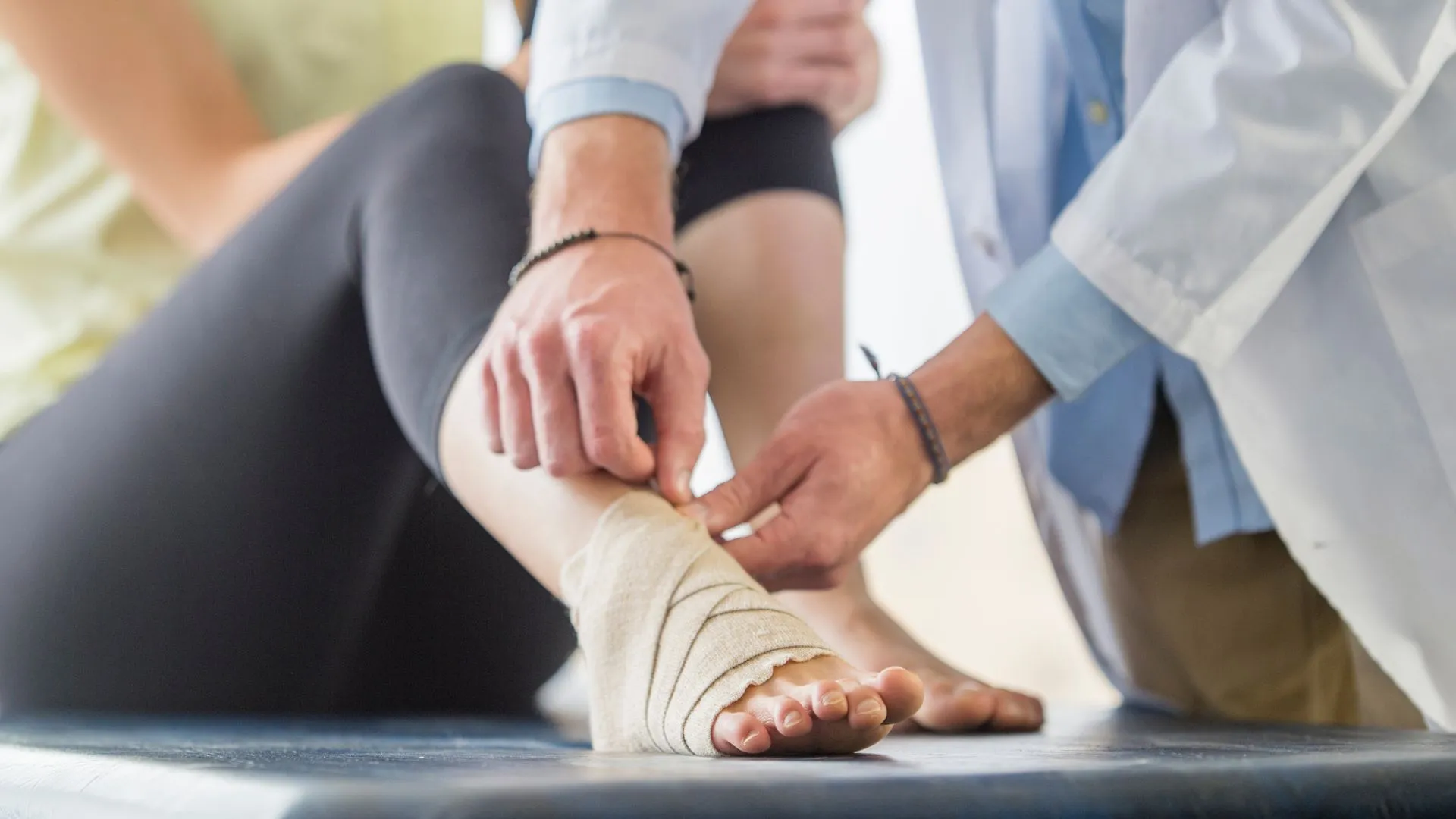 Physio specialist applying bandages to an injured ankle while explaining how comfortable the knee walker is for ankle injuries.