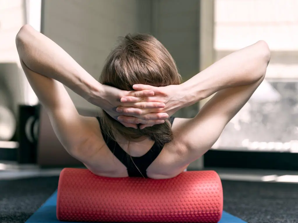 Woman using a foam roller for back tension relief.