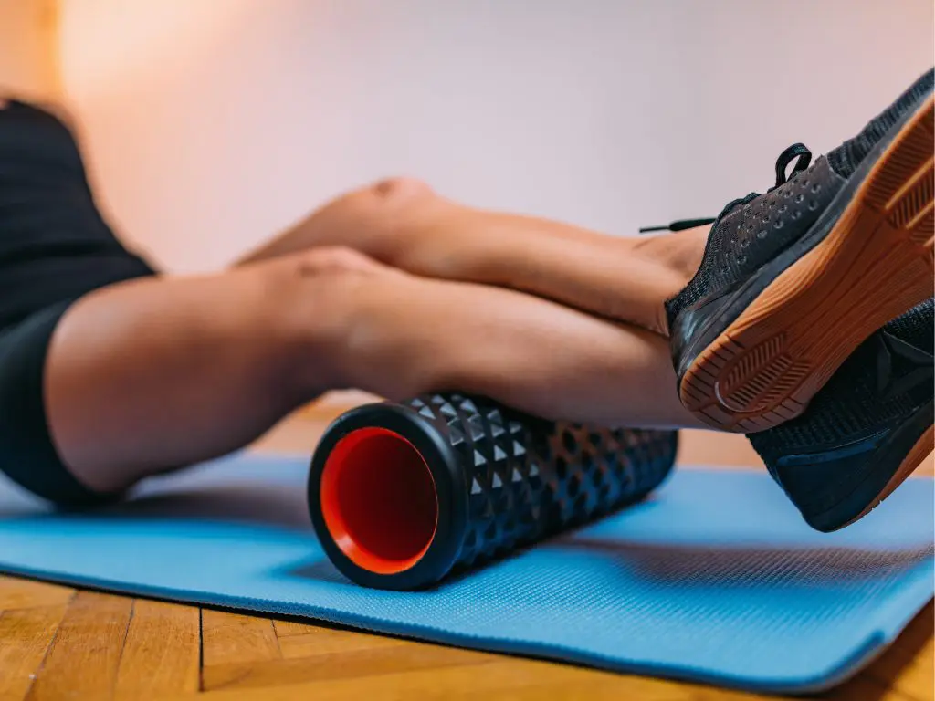 Male using a trigger point massager in black and red colour to relief tension in his calves.