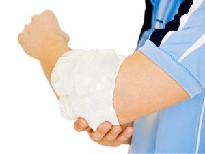 An individual applying a cold ice pack to their elbow, demonstrating the benefits of cold therapy for muscle and joint pain relief.