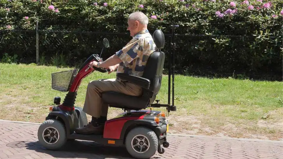 Elderly man using a mobility scooter in the park.