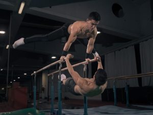 Gymnasts performing advanced exercises on parallel bars, showcasing strength, balance, and agility in a professional training facility.